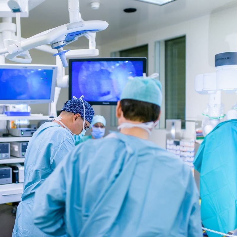 Dr Inan and the surgical team performing incisional hernia repair in the operating room, with operative monitors visible in the background.