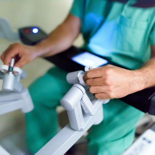 Close-up of the surgeon’s hands controlling robotic instruments for precise minimally invasive inguinal hernia repair.